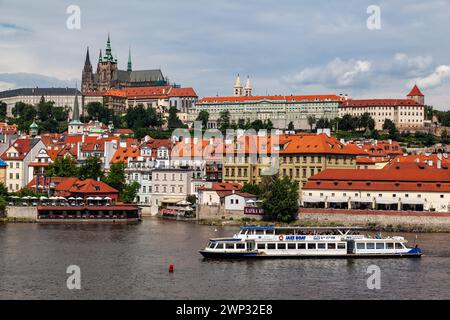 Cathédrale St Vitus, le château, les bâtiments historiques au bord de l'eau dans la petite ville à côté de la rivière Vitava et un bateau touristique, Prague, république tchèque Banque D'Images