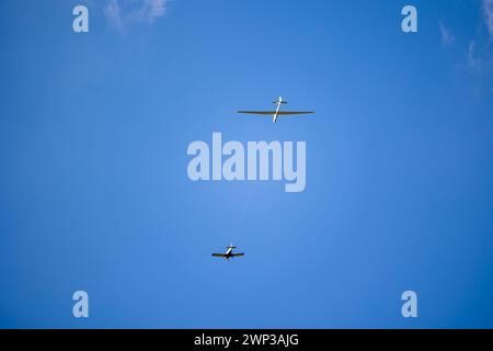 Planeur blanc tiré par un autre petit avion vers le ciel bleu. Planeur tirant sur une journée ensoleillée. Banque D'Images