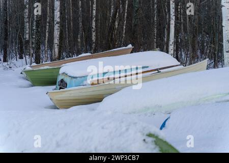 Bateaux à rames recouverts de neige à côté d'une forêt en hiver Banque D'Images