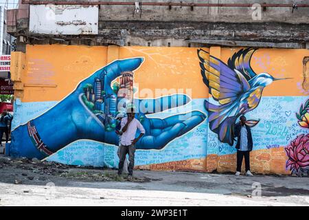 Nakuru, Kenya. 5 mars 2024. Deux hommes se tiennent devant des peintures murales représentant une main tenant une ville et un oiseau volant peint sur un mur dans la ville de Nakuru, créé dans le cadre du projet de ville créative de l'UNESCO de Nakuru pour mettre en valeur le patrimoine culturel et artistique de la ville. Ce travail collaboratif met en vedette les contributions de divers artistes de graffiti dont Bankslave, Joel Bergner, Chelwek, Dante et Natasha Floortje. (Crédit image : © James Wakibia/SOPA images via ZUMA Press Wire) USAGE ÉDITORIAL SEULEMENT! Non destiné à UN USAGE commercial ! Banque D'Images