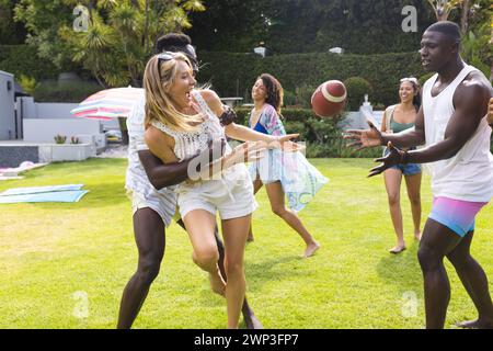 Une jeune femme caucasienne attrape un ballon de football, encouragée par un jeune afro-américain Banque D'Images