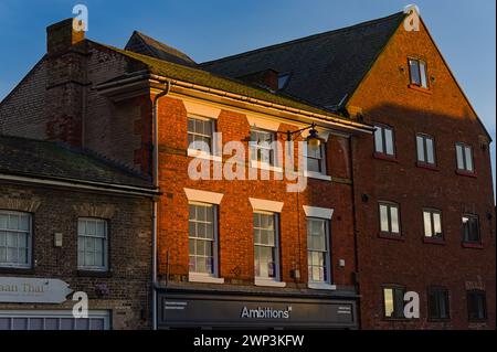 Ancien bâtiment éclairé par le soleil au-dessus d'un magasin Ambitions sur la place Sud de la ville au coucher du soleil Banque D'Images