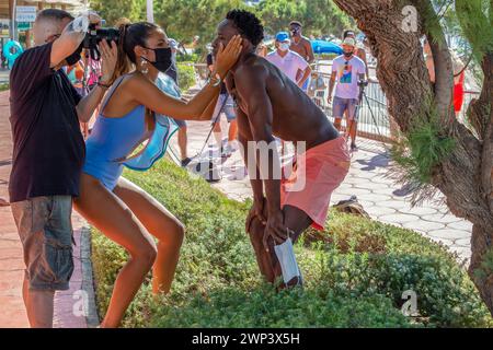 BENIDORM, ESPAGNE - 14 AOÛT 2020 : photographes et mannequins dans une séance de photographie de rue publique avec de nouveaux éléments, masques pandémiques. Banque D'Images