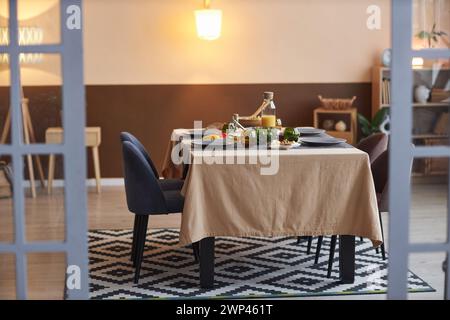 Photo pleine longueur de la petite table à manger sans personne dans le salon confortable tiré à travers l'espace de copie des portes vitrées Banque D'Images