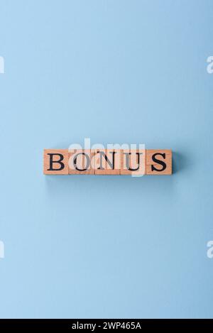 L'inscription Bonus faite de cubes en bois sur un fond Uni. Peut être utilisé pour votre conception Banque D'Images