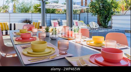 Terrasse arrière et table à manger avec bols, assiettes, verres et argenterie à l'extérieur Banque D'Images