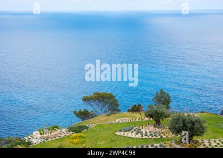 Paisible vue sur la mer avec jardin en terrasses, zones d'herbe verte, lits rocheux et arbres au printemps, jardin de rocaille avec herbes, lavande (Lavandula), romarin Banque D'Images