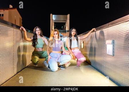 Portrait frontal d'un groupe alternatif de jeunes et cool danseurs hip hop posant sur un pont la nuit Banque D'Images