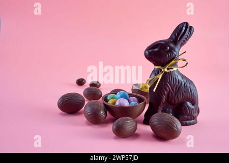 Composition de Pâques avec oeuf en chocolat et lapin sur fond rose. Banque D'Images