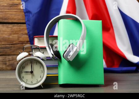 Apprendre une langue étrangère. Différents livres, écouteurs et réveil sur la table en bois près du drapeau du Royaume-Uni Banque D'Images