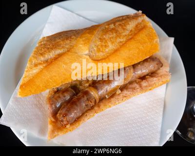 Le snack copieux est une baguette croustillante farcie de saucisses grasses juteuses et d'oignons passionnés. Banque D'Images