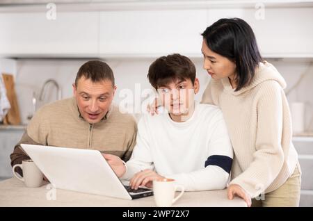 Une famille amicale regarde quelque chose ensemble sur Internet ou des chats vidéo via un ordinateur portable Banque D'Images