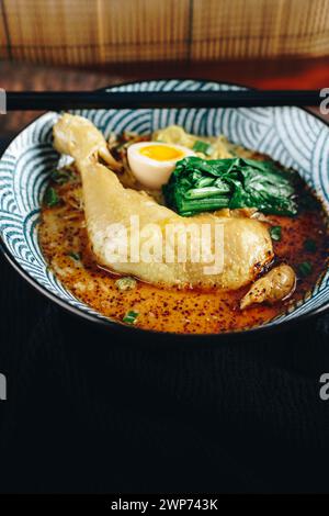 Un bol de soupe avec un morceau de poulet et un légume vert Banque D'Images