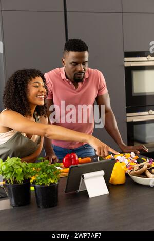 Les jeunes couples afro-américains biraciaux cuisinent ensemble dans une cuisine moderne à la maison Banque D'Images