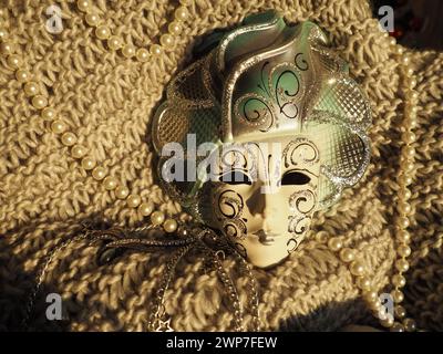 Masque de carnaval sur un fond tricoté avec des perles et des étincelles. Elément de costume de fête de carnaval Banque D'Images