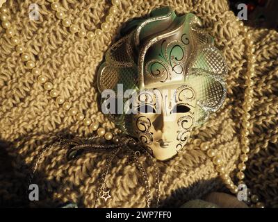 Masque de carnaval sur un fond tricoté avec des perles et des étincelles. Elément de costume de fête de carnaval Banque D'Images