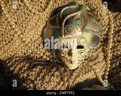 Masque de carnaval sur un fond tricoté avec des perles et des étincelles. Elément de costume de fête de carnaval Banque D'Images