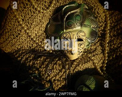 Masque de carnaval sur un fond tricoté avec des perles et des étincelles. Elément de costume de fête de carnaval Banque D'Images