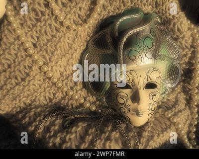 Masque de carnaval sur un fond tricoté avec des perles et des étincelles. Elément de costume de fête de carnaval Banque D'Images