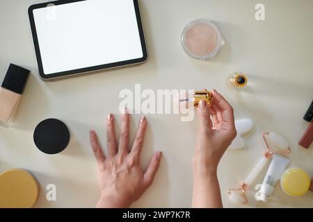 Mains de la femme regardant des vidéos sur tablette lors de la manucure à la maison, vue de dessus Banque D'Images