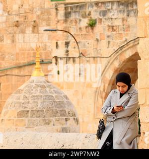 Une jeune femme musulmane regarde son téléphone près du centre Al Aqsa sur le Mont du Temple dans la vieille ville de Jérusalem Banque D'Images