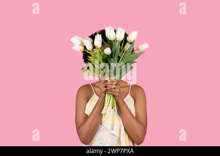 Femme afro-américaine invisible debout derrière un grand bouquet de tulipes blanches fraîches Banque D'Images