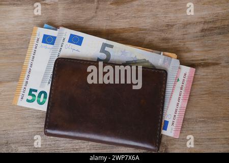 Portefeuille en cuir marron avec billets de banque en monnaie de l'UE, argent comptant de l'Union européenne sur la table en bois, finances dans les affaires et concept d'entrepreneuriat Banque D'Images