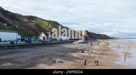 Une vue le long de la plage et la promenade avec des cabanes colorées de plage à Saltburn by the Sea, Angleterre, UK.People marchant le long de la plage. Banque D'Images