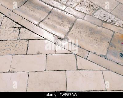 Sol en marbre dans la rue, Dubrovnik, Croatie. Blocs rectangulaires de tuiles de maçonnerie antiques. Roche métamorphique composée de calcite CaCO3. Drainage Banque D'Images