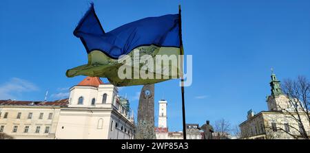 Le drapeau ukrainien agitant en ville contre le ciel bleu Banque D'Images