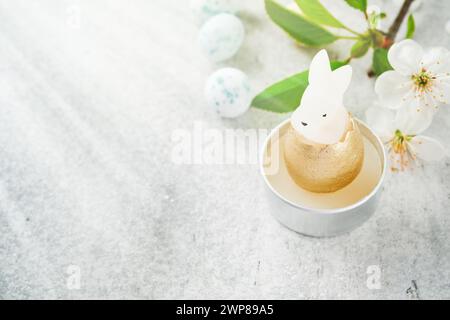 Fond de Pâques de printemps. Pâque fleurissant pomme blanche ou fleur de cerisier et bougie lapin de pâques avec lumière du soleil et rayons sur fond de bois blanc. E Banque D'Images