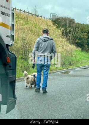 Ipswich, Suffolk - 14 février 2024 : retards importants sur l'A14 en direction ouest à Nacton. Route fermée en raison d'un incident géré par la police. Un homme promène son chien sur l'épaule dure. Banque D'Images