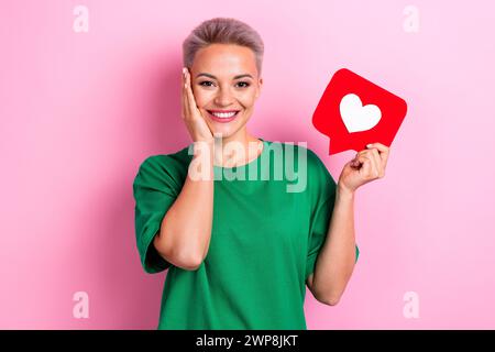 Photo du papier de maintien de joue tactile jolie main positive comme carte de notification isolé sur fond de couleur rose Banque D'Images