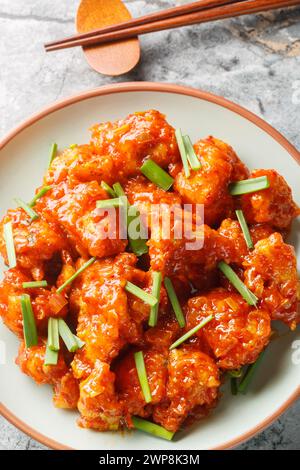 Gobi mandchourie frit frit chou-fleur pané sauté dans une sauce acidulée gros plan sur l'assiette sur la table. Vue de dessus verticale Banque D'Images