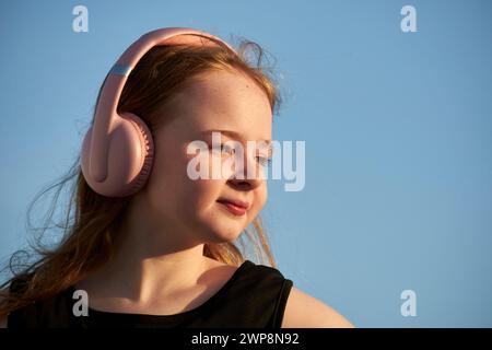 Jeune fille irlandaise britannique de 10 ans portant une robe noire et des écouteurs pendant l'heure d'or coucher du soleil Lanzarote, îles Canaries, espagne Banque D'Images