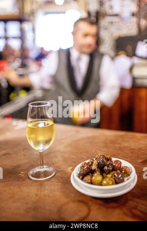 Un verre de fino sherry avec un côté d'olives mélangées sur un bar dans une taverne traditionnelle de Séville. Banque D'Images