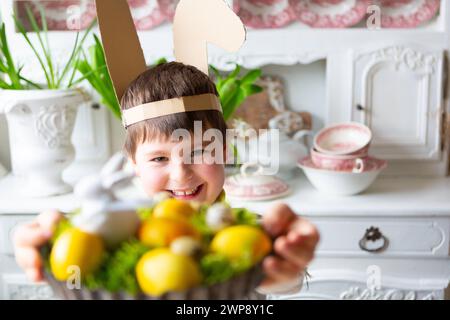 3 mars 2024 : petit garçon tenant un nid de Pâques fait maison avec de la mousse et des œufs de Pâques jaunes. Image symbolique d'une chasse aux œufs *** Kleiner Junge hält ein selbstgemachtes Osternest mit Moos und gelben Ostereiern in der hand. Symbolbild Eiersuche Banque D'Images