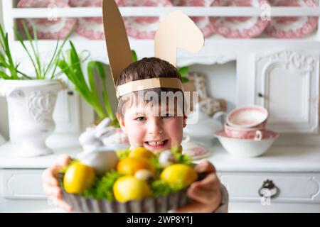 3 mars 2024 : petit garçon tenant un nid de Pâques fait maison avec de la mousse et des œufs de Pâques jaunes. Image symbolique d'une chasse aux œufs *** Kleiner Junge hält ein selbstgemachtes Osternest mit Moos und gelben Ostereiern in der hand. Symbolbild Eiersuche Banque D'Images