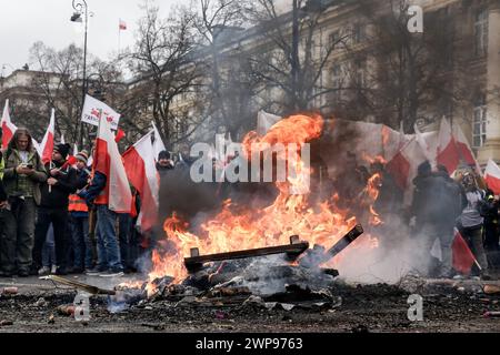 Les agriculteurs polonais descendent dans la rue et brûlent des feux de joie et des flammes de feu pour protester contre le Green Deal de l'UE et une importation de produits agricoles en provenance de pays tiers, dont l'Ukraine, devant le premier ministre Cancellary dans le centre de Varsovie, la capitale de la Pologne, le 6 mars 2024. Banque D'Images