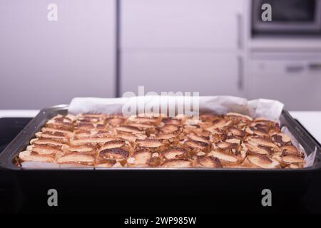 Cuisson de gâteau aux pommes roulé traditionnel avec des noix, des raisins secs et de la cannelle recouverte de neige blanche d'oeuf Banque D'Images