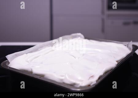 Cuisson de gâteau aux pommes roulé traditionnel avec des noix, des raisins secs et de la cannelle recouverte de neige blanche d'oeuf Banque D'Images