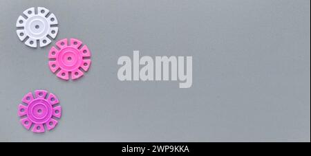 Détails multicolores sous la forme de flocons de neige du concepteur pour enfants sur un fond gris dans la partie gauche de l'image. Blanc et rose Banque D'Images