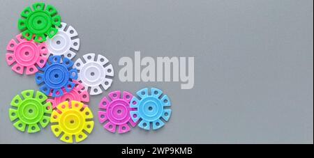 Détails multicolores sous la forme de flocons de neige du concepteur d'enfants sur un fond gris.Rouge, jaune, vert, bleu, blanc, disques en plastique rose Banque D'Images