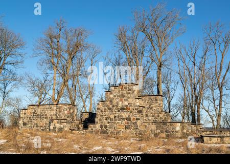 Flasta Medieaval église ruine entourée de chênes. Journée ensoleillée avec des taches de neige sur le sol. Banque D'Images