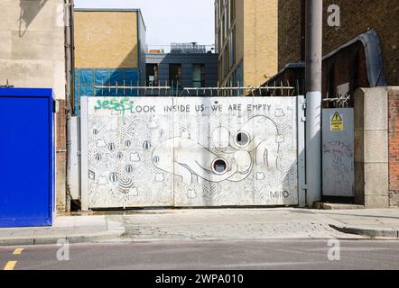 Londres, Angleterre, Royaume-Uni - 4 mai 2014 : graffiti conceptuel noir et blanc représentant la vie moderne (créé par MIIIO) sur la porte dans la région de Brick Lane. Art urbain Banque D'Images