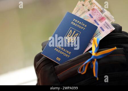 Passeport biométrique ukrainien et factures d'argent UAH sur sac à dos touristique de près Banque D'Images
