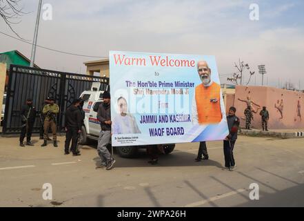 Srinagar, Inde. 06 mars 2024. Les gens tiennent une palissade publicitaire pour l'accueil du premier ministre indien Narendra Modi à Srinagar. Les agents de sécurité sont sur leurs gardes à travers la vallée du Cachemire avant la première visite du premier ministre indien Narendra Modi dans la vallée depuis l'abrogation de l'article 370 en 2019, mettant fin au statut spécial semi-autonome de la région. Crédit : SOPA images Limited/Alamy Live News Banque D'Images