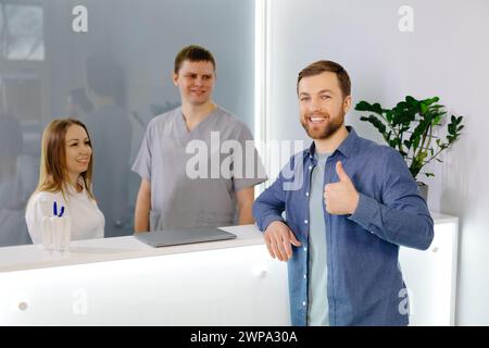 Patient reconnaissant. Homme debout à la réception de la clinique dentaire et très heureux pour le traitement Banque D'Images