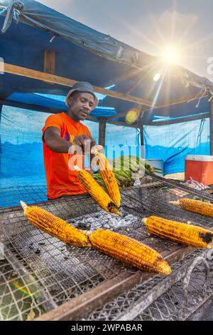 vendeur de rue africain griller du maïs doux sur le bord de la route dans une cabane Banque D'Images