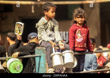 Rafah, Gaza. 06 mars 2024. Des enfants palestiniens attendent de recevoir de la nourriture préparée par une cuisine caritative dans un contexte de pénurie de vivres, à Rafah, dans le Sud de la bande de Gaza, mercredi 6 mars 2024. Les approvisionnements alimentaires, compte tenu de la poursuite du grave siège israélien, sont insuffisants dans la bande de Gaza. Photo de Ismael Mohamad/UPI crédit : UPI/Alamy Live News Banque D'Images